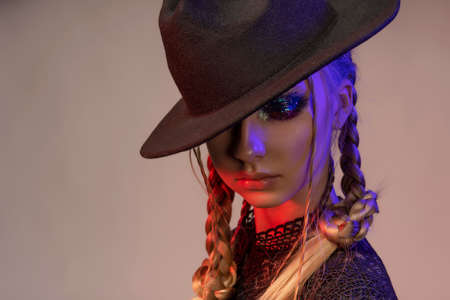 Conceptual portrait of a beautiful teenage girl wearing a black dress and a black hat. It is...