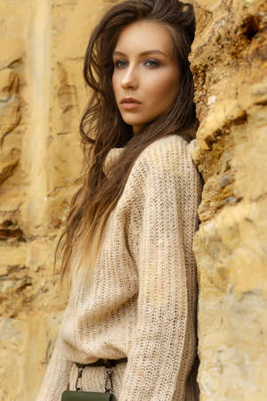Beautiful girl wearing a beige sweater and a black skirt with a pattern in the form of large flowers...