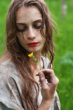 Beautiful young dirty mad and manic looking girl wearing torn clothes and smeared with mud and dried...