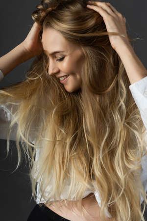 Closeup portrait of a smiling young pregnant beautiful blonde woman wearing a white shirt joyfully...