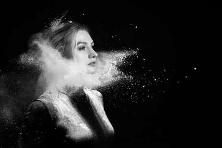 Beautiful slim girl wearing a gymnastic bodysuit covered with clouds of the flying white powder...