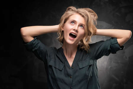 Beautiful young blonde girl with disheveled hairstyle and nude makeup, wearing a shirt and jeans...