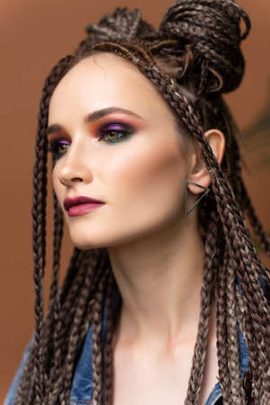 Close up portrait of a beautiful girl with an afro cornrows hairstyle, wearing a casual denim jacket, near to a palm tree leaves. Fashionable, commercial, modern designの写真素材