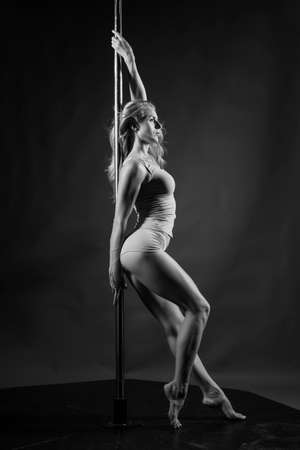 Beautiful athletic busty elegant blonde girl performs artistic elements of an exotic dance on a gray background. Health, lifestyle, sports black and white monochrome design. Copy spaceの写真素材
