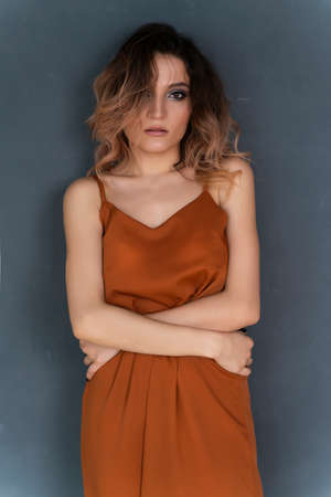 Beautiful girl wearing a trendy casual dress posing against a gray wall. Fashionable, advertising and commercial designの写真素材
