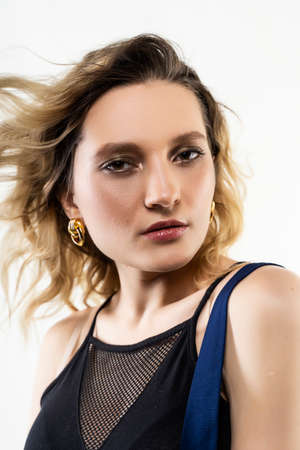 A beautiful girl wearing a black and blue casual trendy dress sensually poses in the wind at the...