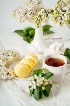 Yellow macaroon cookies among white flowers of lilac and green leaves. Food photography. Advertising and commercial close up designの写真素材