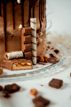 Chocolate cake decorated with various cookies and nuts on a glass plate standing on a white cloth. Food photography. Advertising and commercial close up designの写真素材