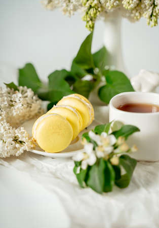 Yellow macaroon cookies among white flowers of lilac and green leaves. Food photography. Advertising and commercial close up designの写真素材