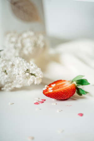 Sliced strawberry, on a white cloth, near the flowers of lilac. Food photography. Advertising and commercial close up designの写真素材