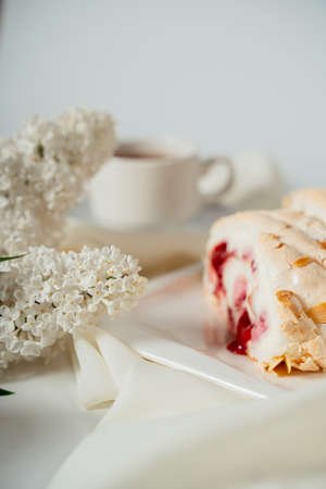 Fruit jam meringue cake garnished with hazelnut chips, among lilac flowers. Food photography....