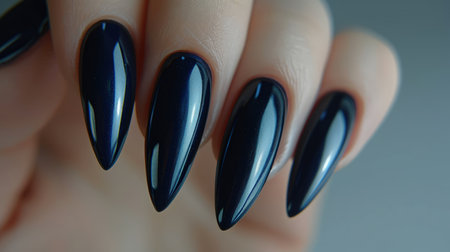Elegant stiletto nails painted in a shiny navy blue, showcasing a glamorous and trendy manicure.の素材