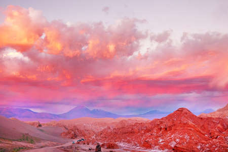 Panoramic view of the Mars Valley near San Pedro de Atacama against a warm and colorful sunset sky above volcanoes.の写真素材