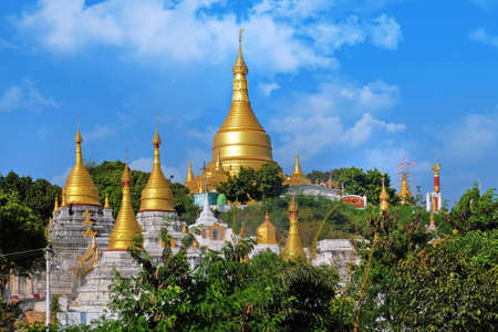 View of the golden roof of a Burmese Pagoda in Mingun, Mandalay, against a blue sky.の写真素材