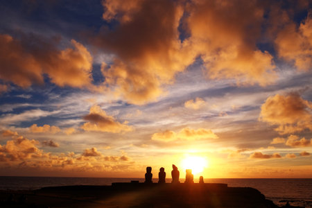 Moai statues at the museum entrance near Ahu Tahai Ceremonial complex on Easter Island, against a colorful sunset sky.の写真素材