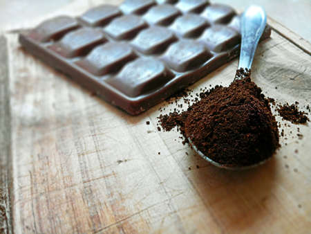 A Chocolate Bar Near a Spoon Full Of Cocoa Powder