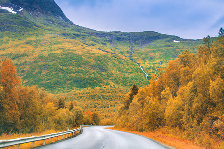 Autumn road in mountains. Colorful autumn landscape with narrow empty road.の写真素材