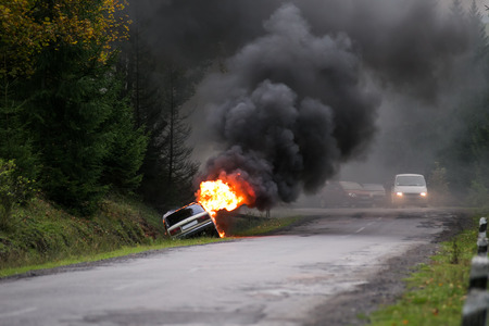 Car crash. Car burning on road. Thick black smoke from car in fire.の写真素材