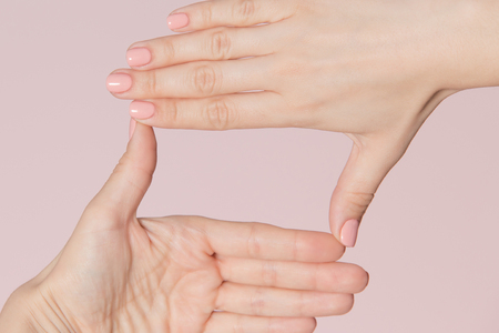 Woman hands making square frame isolated on pink background. Manicure advertising concept.の写真素材
