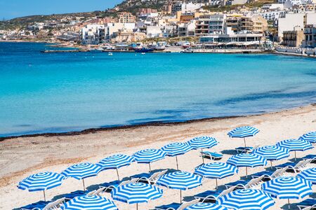 Malta. Maltese beach. Blue sun umbrellas on beach on blue sea background. Resort background.の写真素材