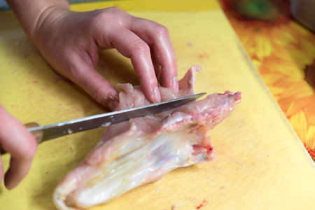 Cutting into pieces of fresh chicken on a yellow boardの写真素材