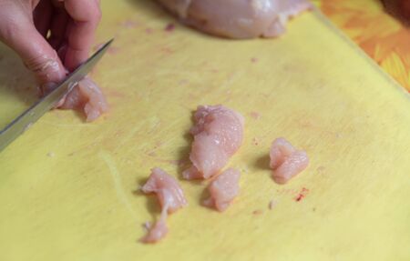 Cutting fresh chicken on a yellow boardの写真素材