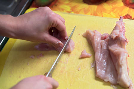 Slices of fresh chicken on a yellow boardの写真素材