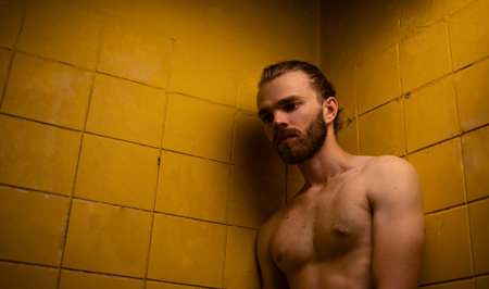 Brutal man against yellow tiles in contrast light