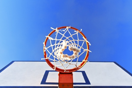 Bottom view of a basketball hoop against a blue skyの写真素材