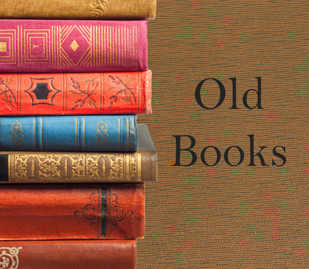 Stack of old variegated books on brown textured backgroundの写真素材
