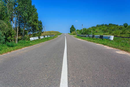 Rural road through a forest at daytime horizontalの写真素材