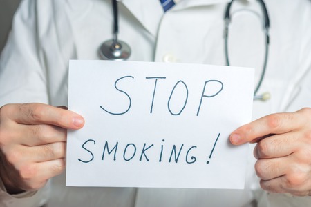 Doctor holds white clipboard with stop smoking labelの写真素材