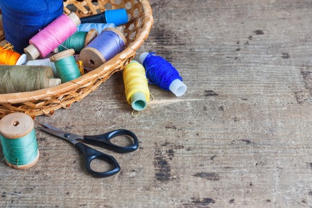 Bobbins with thread and scissors. Sewing tools on the old wooden surface. Vintage background