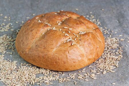 White bread and grains of wheat lying on a sacking