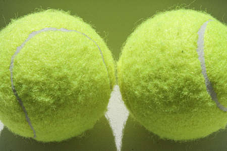 Two golden tennis balls on a white background