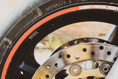 Motorcycle wheel and brake disc close-up. Black tire with a red stripe.