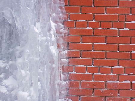 The red brick wall is covered with ice. The house froze. The wall is frozen.の写真素材