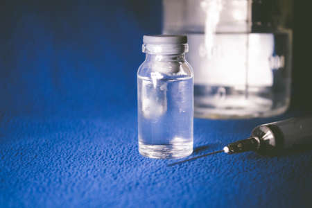 Vaccine in vitro. Medicine in a flask on a blue background. Antibiotic vial for disease. Vaccination...