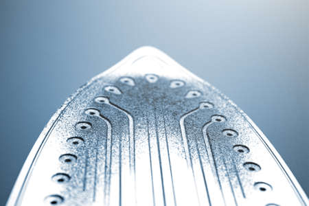 Iron with traces of burnt fabric. Melted fabric on the sole of the iron. On a white background.の写真素材