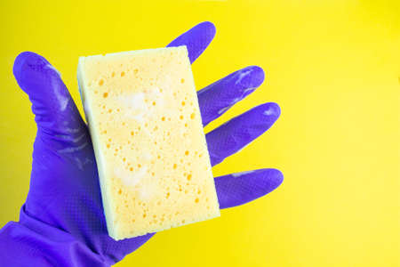 Hand in a rubber glove for cleaning. Kitchen sponge in hand. Spray bottle for window cleaning. Foam sponge in hand on isolated background.の写真素材