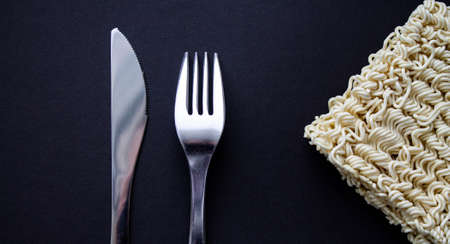 Noodles on a plate. Vermicelli in the shape of a square on a round plate. Fork and knife and noodles...
