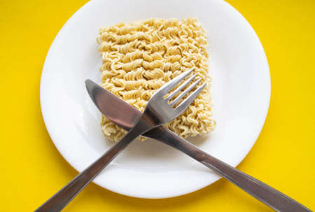Noodles on a plate. Vermicelli in the shape of a square on a round plate. Fork and knife and noodles...