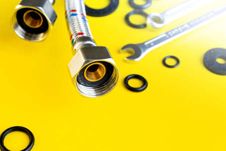 Plumbing repair at home. Water inlet hoses and rubber gaskets on the table. Wrenches and rubber for screwing on the water hoses.の写真素材