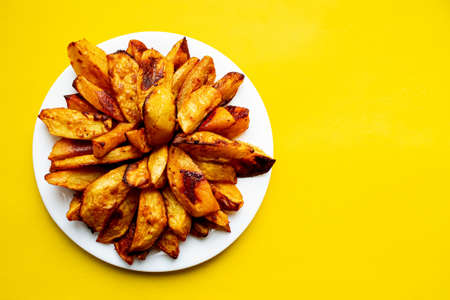 Fried fries and tomato sauce on a yellow background. Fast food. Rustic potatoes baked in the oven. Sliced and fried potatoes.の写真素材
