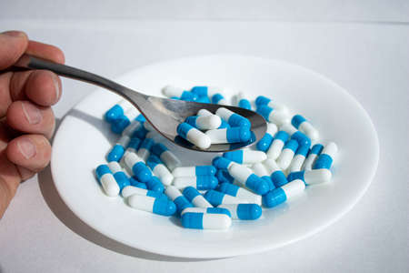 Tablets on a plate. Medicine for the patient on a spoon. Tablet on a spoon.の写真素材