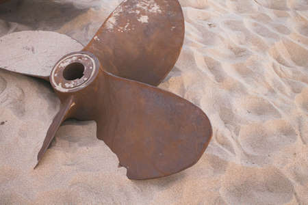Old ship engine propeller. Rusty blades in the sand. Wreckage of a ship in the ocean. Sunken ship at...