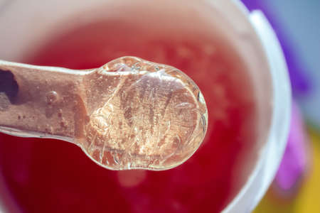 Sugar paste for hair removal. Shugaring paste close-up. Liquid sugar flows down a wooden spatula....