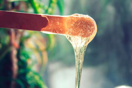 Sugar paste for hair removal. Shugaring paste close-up. Liquid sugar flows down a wooden spatula....
