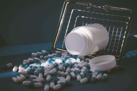 Pills in a grocery basket. Medicine capsules on the table. Buyer at the pharmacy. Ordering medicines online. Pills on a blue background in a box.の写真素材