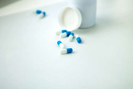 The pills spilled out of the jar. Medical capsules on the table. Pharmaceuticals. Prescription from a doctor. Treatment of diseases with pills.の写真素材